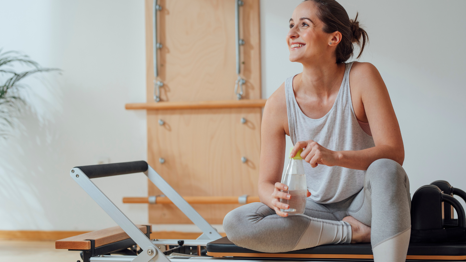 ピラティス器具に手を添えて伸びる女性