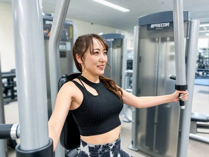 チェストプレスで押す動作を体験する会員とスタッフ